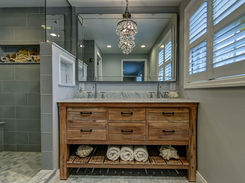 bathroom-remodel-gray-tile-wood-vanity-beveled-mirror-bathroom-chandelier