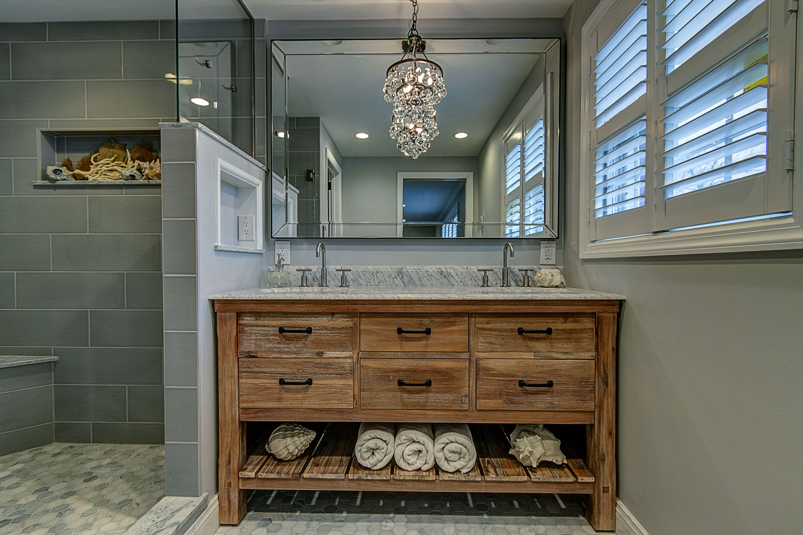 bathroom-remodel-gray-tile-wood-vanity-beveled-mirror-bathroom-chandelier