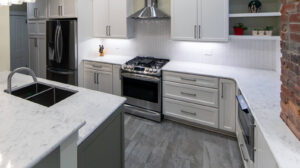 View of a remodeled kitchen featuring marble countertops, herringbone tile backsplash, and built-in wine storage.