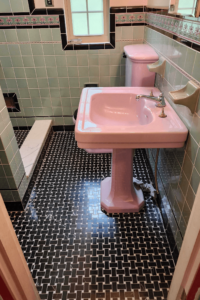 Renovated bathroom with basketweave floor tile and vintage sink and toilet.