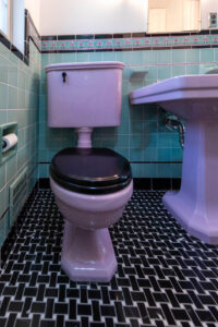 Renovated bathroom with basketweave floor tile and vintage sink and toilet.