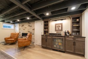 View of a lower level family room featuring an open, painted ceiling, tiled fireplace wall, and comfortable seating area.