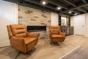 View of a lower level family room featuring a tiled fireplace wall with two retro seats in front of it.
