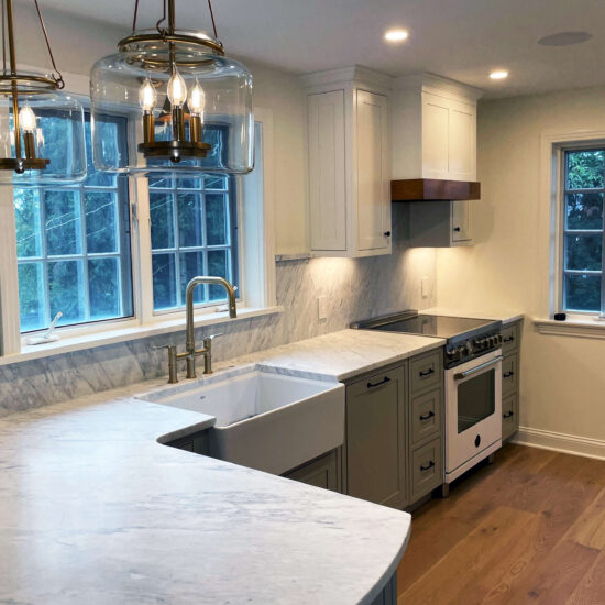 Beautifully remodeled kitchen with grey cabinets and white marble countertop and backsplash.