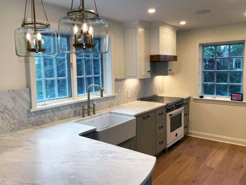 Beautifully remodeled kitchen with grey cabinets and white marble countertop and backsplash.