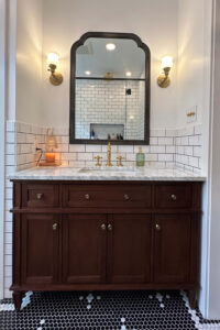 View of a new vanity and mirror in a remodeled bathroom.