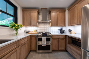 View of newly remodeled kitchen with wood cabinets and decorative backsplash tile.