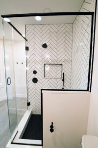 Side view of the modern black and white tiled shower in a newly remodeled bathroom.