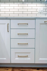 Close up of the white drawers with gold hardware in a newly remodeled kitchen.