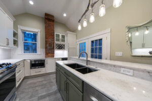 View of a remodeled kitchen featuring marble countertops, herringbone tile backsplash, and built-in wine storage.