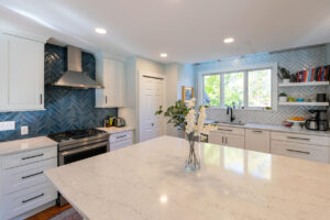 Close up of the large island in a newly remodeled kitchen featuring white cabinetry and marble countertops.