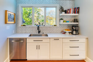 view of the bay window above the sink in a newly remodeled kitchen featuring white cabinetry and marble countertops.