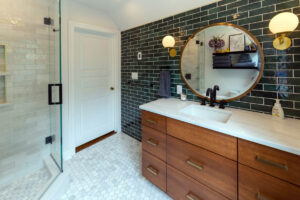 View of a recent bathroom renovation in Pittsburgh that includes a wood vanity, tile floor, custom corner shower, and floating shelves.