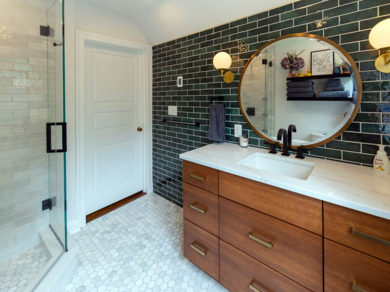 View of a recent bathroom renovation in Pittsburgh that includes a wood vanity, tile floor, custom corner shower, and floating shelves.