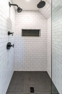 Close up of a walk-in shower that features black and white tile.