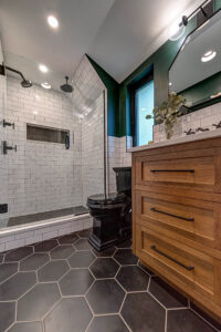 View of a bathroom in Pittsburgh that features black and white tile, a walk-in shower, and wood vanity.