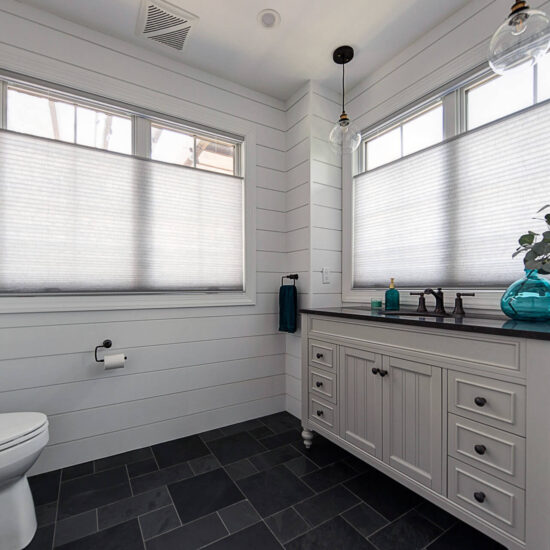 View of powder room with shiplap walls, a large-format tile floor, and big windows.