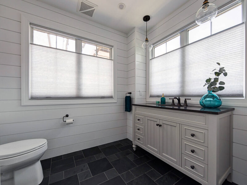 View of powder room with shiplap walls, a large-format tile floor, and big windows.