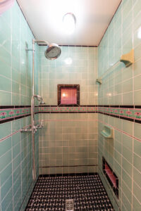View of the tiled shower in a renovated bathroom with vintage style.
