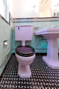 Renovated bathroom with basketweave floor tile and vintage sink and toilet.