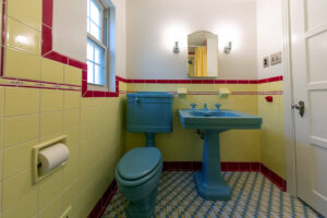 Renovated bathroom with vintage style tile, colored ceramic sink and toilet, and mosaic floor.