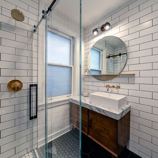 View of a sleek bathroom with white subway tile, glass shower enclosure, and modern vanity.