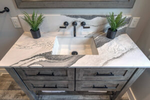 View of a marble sink in a newly remodeled bathroom with natural plant decor.