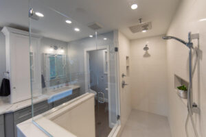 Broad view of a newly remodeled bathroom with white tile and wood floor.