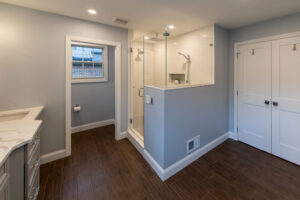 View of the outside of an oversized shower with glass half wall.