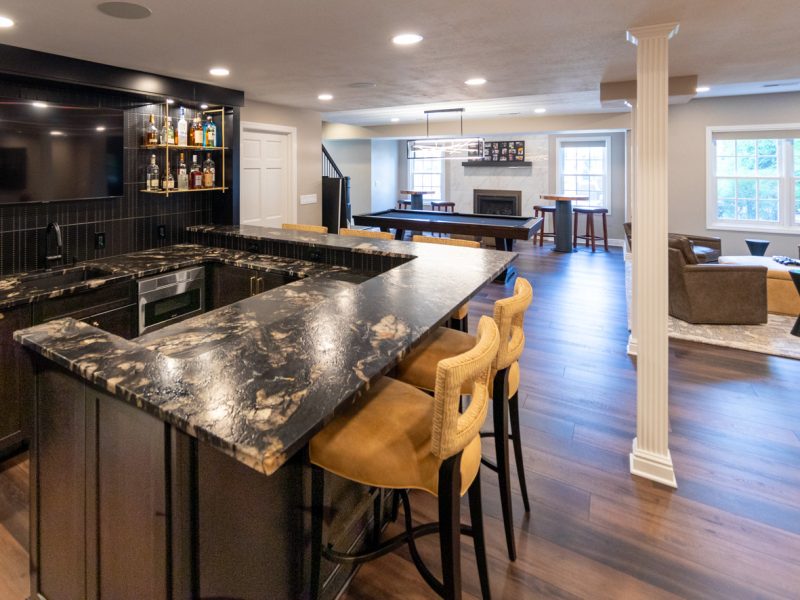 View of a renovated basement with a family room, bar, game room, and bathroom.