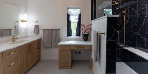 View of master bathroom with a walk-in black shower and gold finishes.