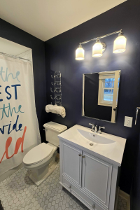 View of a remodeled bathroom featuring a white tiled shower, marble floor tile, vanity and toilet.