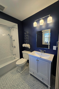 View of a remodeled bathroom featuring a white tiled shower, marble floor tile, vanity and toilet.