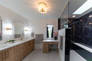 View of master bathroom with a walk-in black shower and gold finishes.