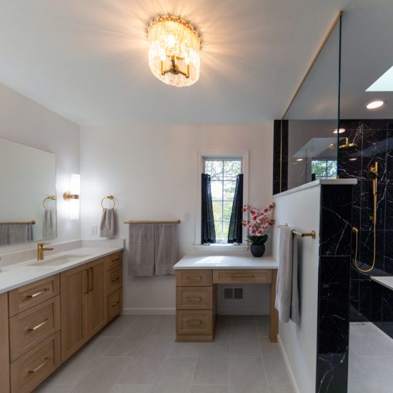View of master bathroom with a walk-in black shower and gold finishes.