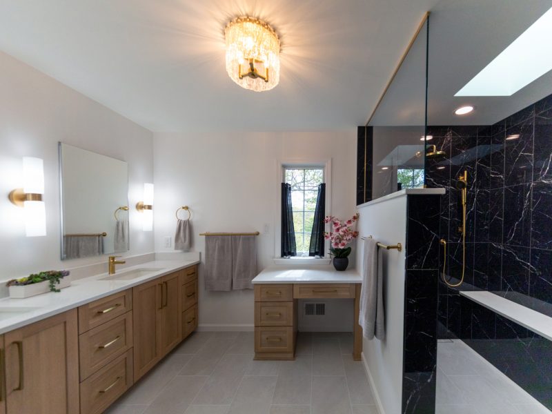 View of master bathroom with a walk-in black shower and gold finishes.