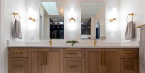 Close-up view of the double vanity in a newly remodeled master bathroom with a walk-in black shower and gold finishes.