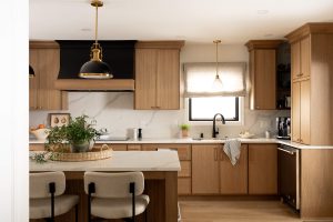 Remodeled kitchen with a large island, warm cabinetry, and black and gold accents.
