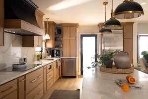 Remodeled kitchen with a large island, warm cabinetry, and black and gold accents.