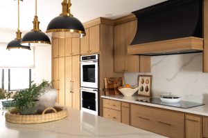 Remodeled kitchen with a large island, warm cabinetry, and black and gold accents.