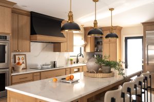 Remodeled kitchen with a large island, warm cabinetry, and black and gold accents.