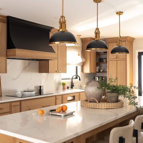 Remodeled kitchen with a large island, warm cabinetry, and black and gold accents.