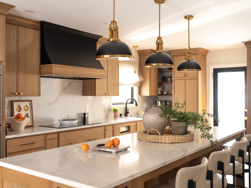 Remodeled kitchen with a large island, warm cabinetry, and black and gold accents.