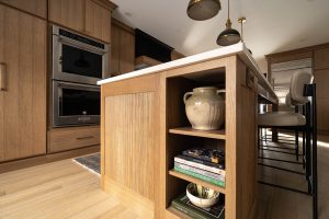 Remodeled kitchen with a large island, warm cabinetry, and black and gold accents.