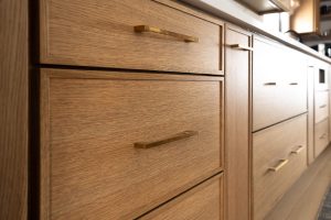 Remodeled kitchen with a large island, warm cabinetry, and black and gold accents.