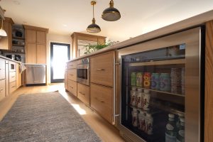Remodeled kitchen with a large island, warm cabinetry, and black and gold accents.