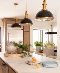 Remodeled kitchen with a large island, warm cabinetry, and black and gold accents.
