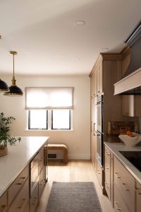 Remodeled kitchen with a large island, warm cabinetry, and black and gold accents.