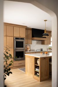 Remodeled kitchen with a large island, warm cabinetry, and black and gold accents.