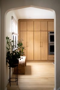 Remodeled kitchen with a large island, warm cabinetry, and black and gold accents.